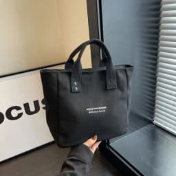 A Casual Canvas Tote Bag with a Bell Pendant and Zipper Closure; This Stylish and Durable Tote Bag Is Perfect for School and Work