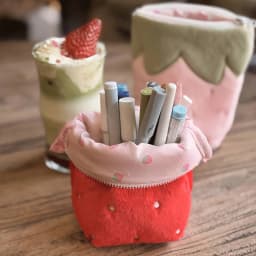 Japanese vintage-style strawberry vertical pencil case, made of soft plush material, available in pink and red colors. The vertical design is stable and won't tip over. It has a large capacity to store stationery, mobile phones, cosmetics, journal materials, and CCD card cameras. It is shockproof, scratch-resistant, portable, and multi-purpose. Sweet, cute, and practical, it is suitable for daily study, office work, and travel