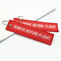 100Pcs “Remove Before Flight” embroidered red fabric keychain with white text – versatile tag for bikes, cars & bags key ring