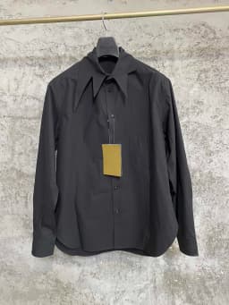 An independent designer of a long, dark leaf-collared shirt