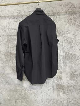 An independent designer of a long, dark leaf-collared shirt