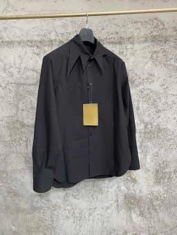 An independent designer of a long, dark leaf-collared shirt