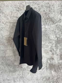 A simple long-sleeved single-breasted shirt with a double-layered collar, solid color and asymmetrical design