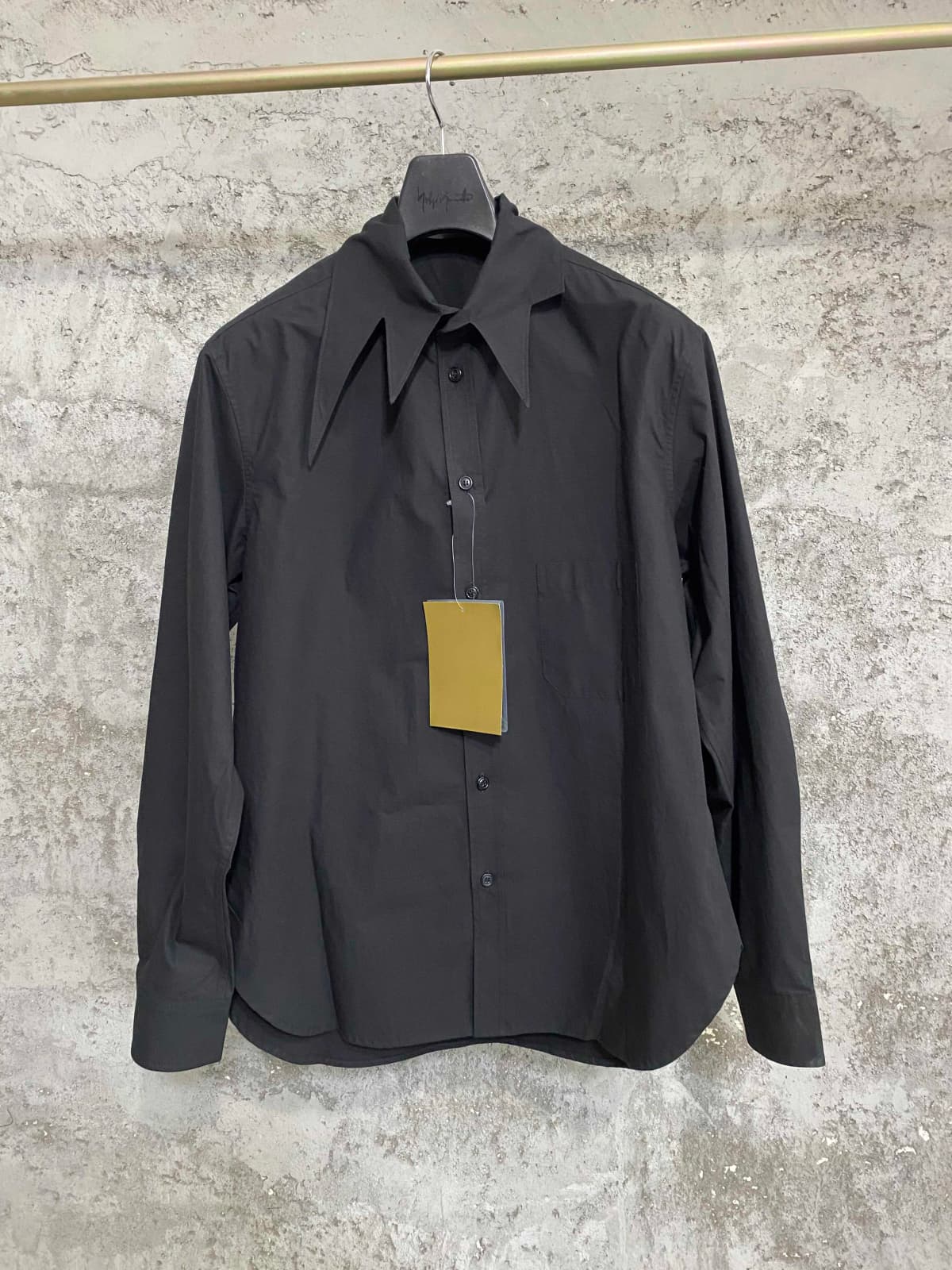 An independent designer of a long, dark leaf-collared shirt